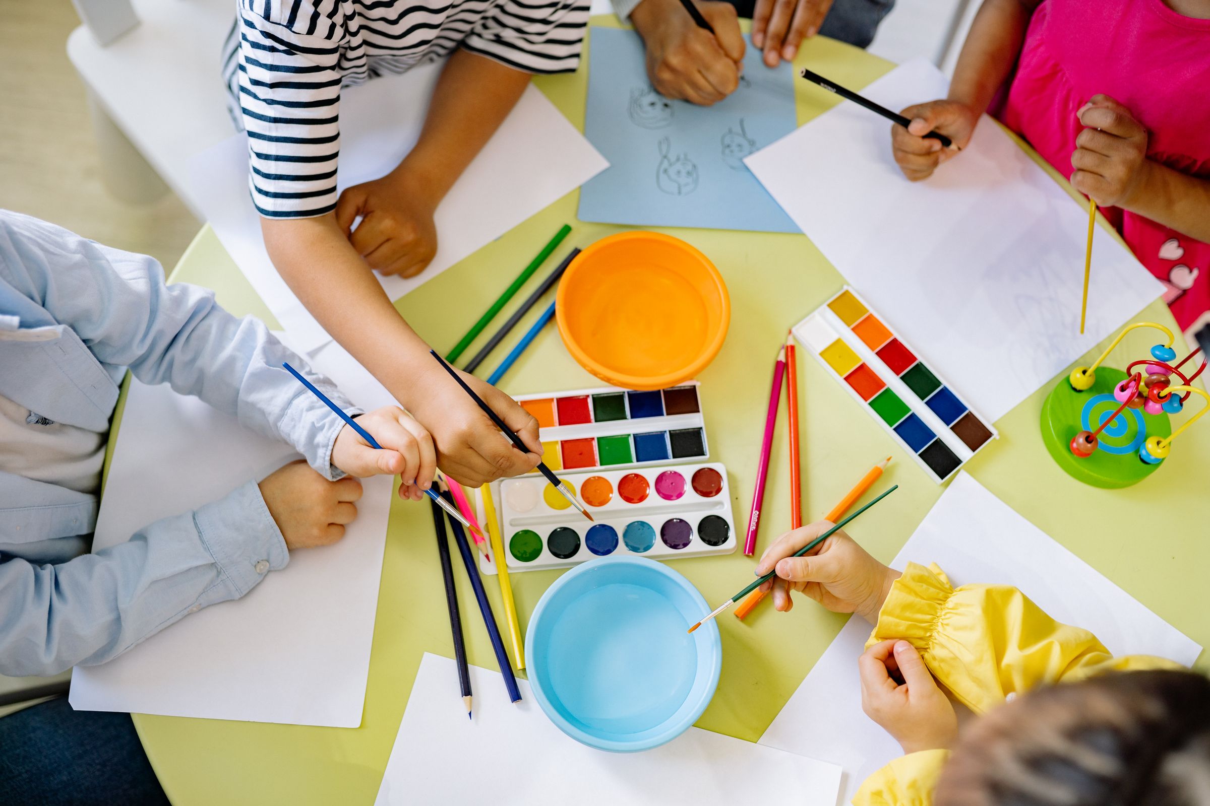 Young children painting with watercolours at a table